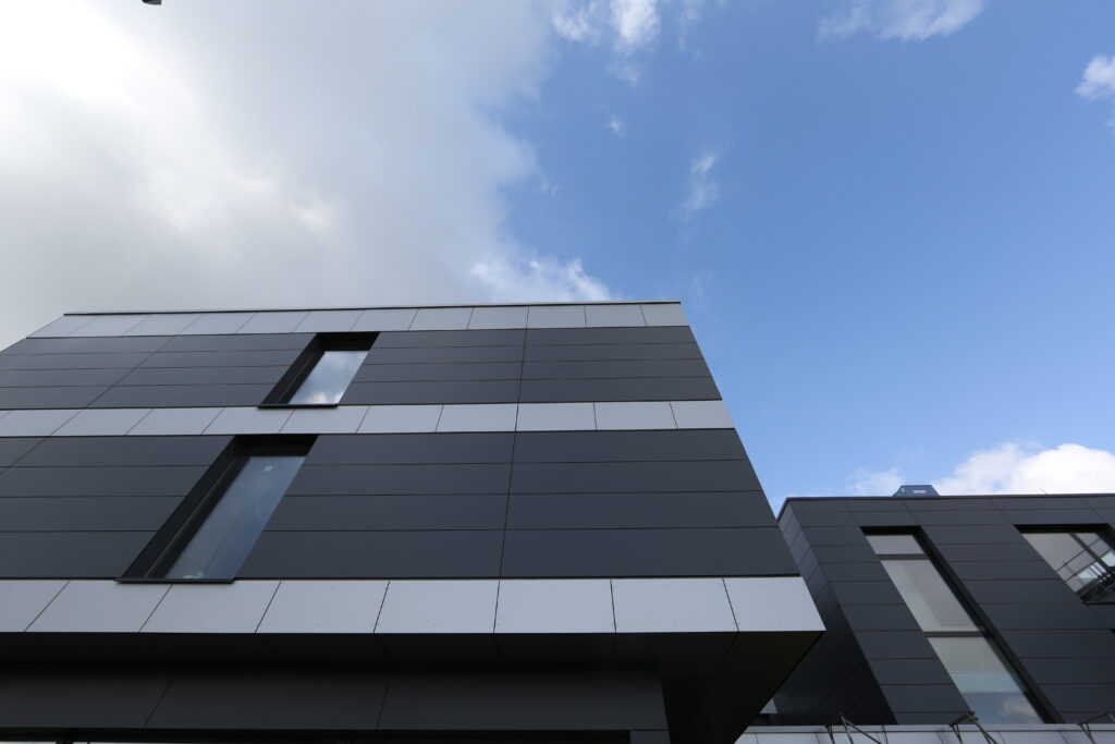 Das EconoMy-Hotel ist ein modernes Gebäude mit zweifarbig grauer Verkleidung. Die Außenansicht zeigt die tiefen Fenster der Zimmer.